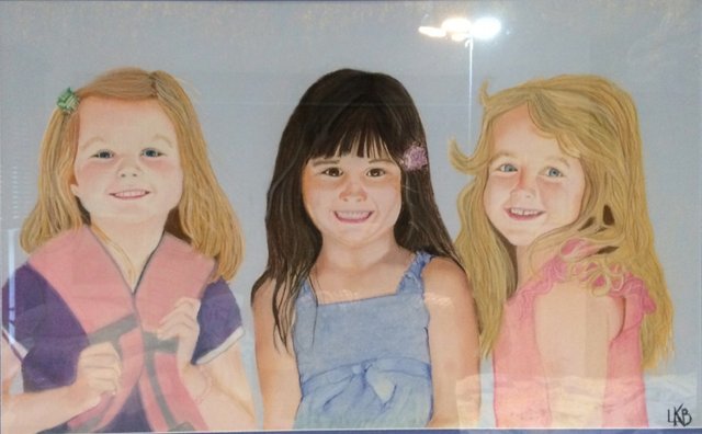 Three smiling little girls standing shoulder to shoulder.